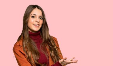 Seyir doğru izole pembe arka plan üzerinde gülümseyen iken bir fikir sunmak montlu genç kadın