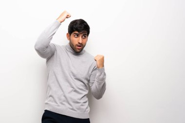 Genç adam bir zaferini kutluyor izole beyaz duvar üzerinde