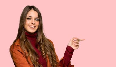 Genç kadın yan yan pozisyonda izole pembe bir arka plan üzerinde kat işaret parmağı