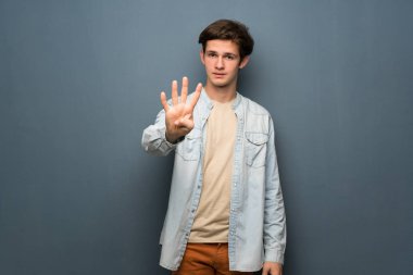 Jean ceket gri duvar mutlu ve sayım dört parmak ile üzerinde olan genç adam