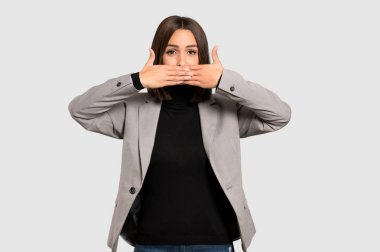 Uygunsuz bir şey izole gri arka plan üzerinde söylediğin için el ile ağız kapsayan genç iş kadını