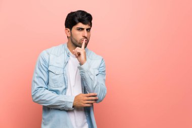 Pembe duvar bir işaret parmağını ağzına koyarak sessizlik jest gösteren genç adam