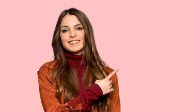 Ürün yalıtılmış pembe arka plan üzerinde sunmak için genç kadınla tarafına işaret eden kat