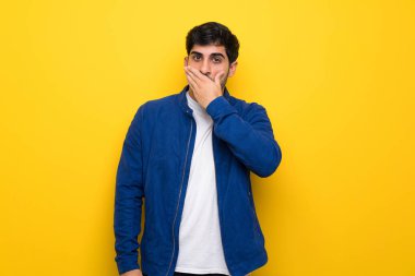 Mavi ceket ve sarı duvar eller ile ağız kaplama üzerinde olan adam