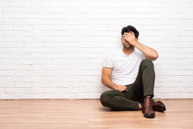 Yerde oturan genç adam elleriyle gözlerini kapatıyor. Bir şey görmek istemiyorum.