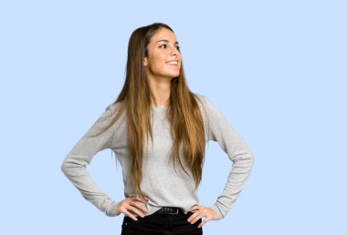 kalça, silah ile poz ve mavi zemin üzerine gülen genç kız