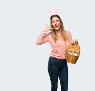 Tavşan kulakları telefon jest yapma Paskalya tatili için giyen genç kadın. Bana arka işaret izole gri arka plan üzerinde de