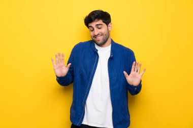 Mavi ceket ve sarı duvar gülümseyen üzerinde olan adam