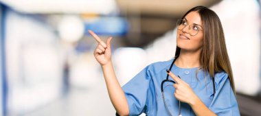 İşaret parmağı ile işaret ve bir hastanede ararken genç hemşire