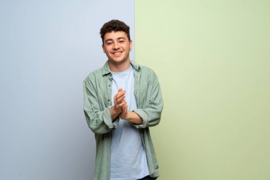 Genç adam bir konferansta sunum sonrası applauding mavi ve yeşil arka plan üzerinde