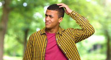 Genç afro Amerikalı adam baş bir parkta tırmalamak süre şüpheleri