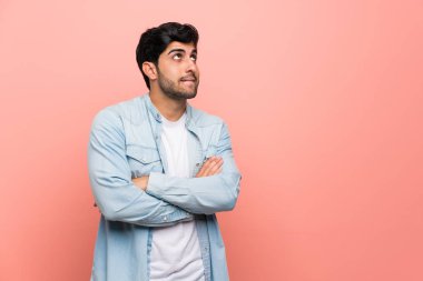 Genç adam karıştırmayın yüz ifadesi ile pembe duvarın üzerinden