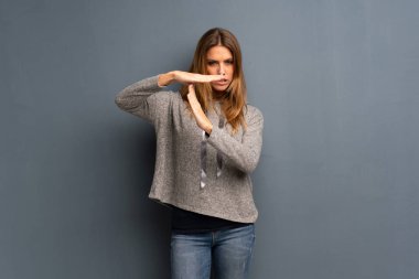 Zaman aşımı jest yapma gri arka plan üzerinde sarışın kadın