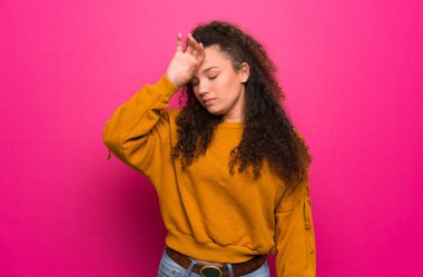 Genç kız yorgun ve hasta ifade ile pembe duvar üzerinde