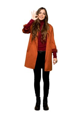 Bir ok işareti parmak ile izole beyaz arka plan üzerinde gösterilen montlu genç kadının tam uzunlukta atış