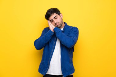 Mavi ceket ve sarı duvar yapım uyku hareketle dorable ifade üzerinde olan adam