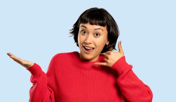 電話のジェスチャーを作る 分離された青の背景に赤のセーターと短い髪の女の子 — ストック写真