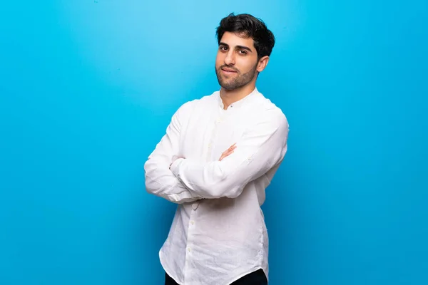 Joven Sobre Aislada Pared Azul Manteniendo Los Brazos Cruzados Posición —  Fotos de Stock