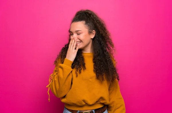 Teenager girl over pink wall smiling a lot