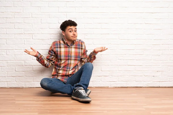 Mladý Muž Sedí Podlaze Tvorby Nepochybuje Gesto — Stock fotografie