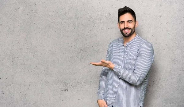 Elegant man with shirt presenting an idea while looking smiling towards over textured wall