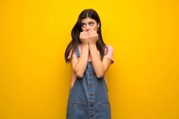 Nastolatek Dziewczyna Nad Żółte Ściany Nerwowy Przerażony Włożenie Ręki Buzi — Zdjęcie stockowe
