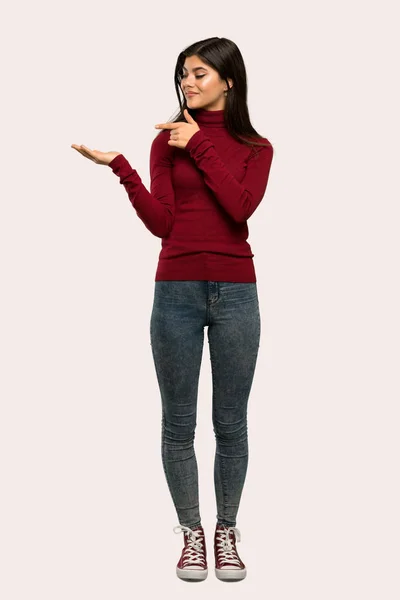 一个少年女孩的全长镜头与高领毛衣持有复制空间想象的手掌插入广告在孤立的背景 — 图库照片