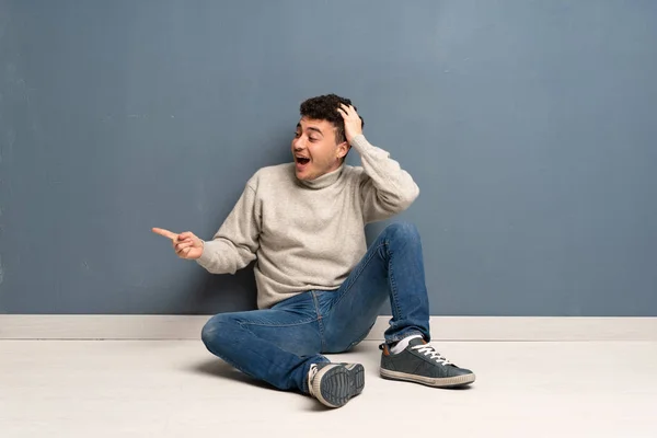 Jonge Man Zittend Vloer Verrast Wijzende Vinger Naar Kant — Stockfoto