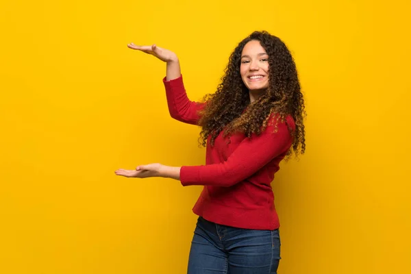 Adolescente Chica Con Suéter Rojo Sobre Pared Amarilla Celebración Copyspace —  Fotos de Stock