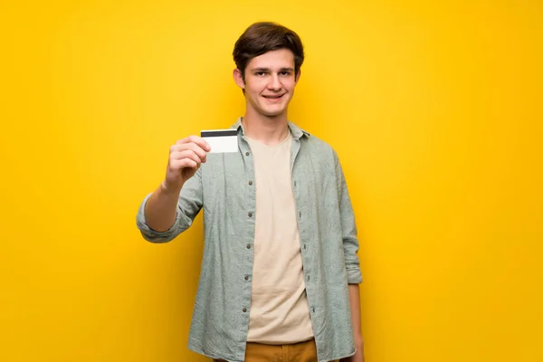 Dospívající Muž Nad Žluté Zdi Drží Kreditní Karty — Stock fotografie