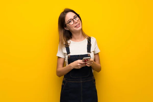 Kobieta Nad Żółte Ściany Wysłanie Wiadomości Telefonu — Zdjęcie stockowe