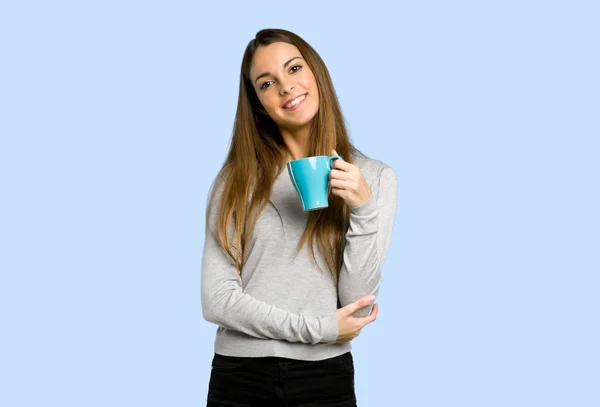 青の背景にコーヒーのホットカップをもつ少女 — ストック写真