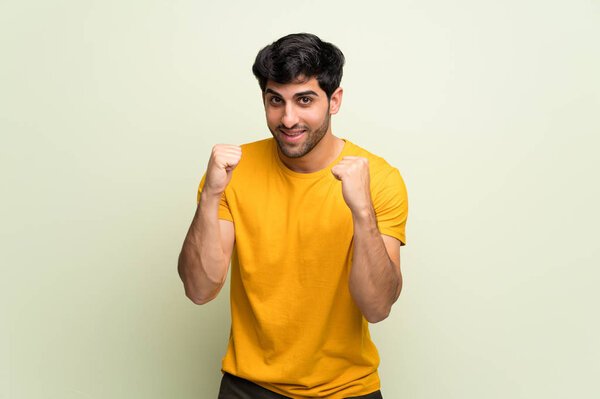 Young man over pink wall celebrating a victory in winner position