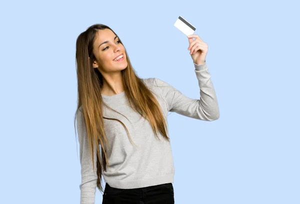 Jong Meisje Houdt Van Een Credit Card Denken Blauwe Achtergrond — Stockfoto