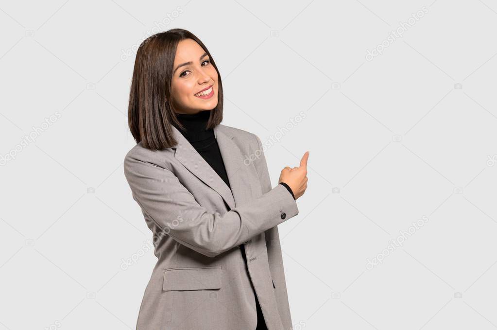 Young business woman pointing back on isolated grey background
