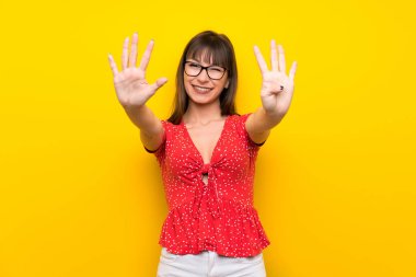 Genç kadın dokuz parmaklı sayma sarı duvarın üzerinden