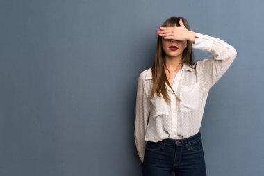 Mavi duvar üzerinde gözlüklü kadın gözleri elle kaplayan. Bir şey görmek istemiyorum