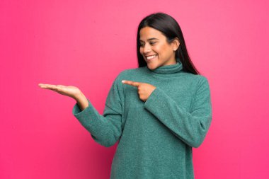 Genç Kolombiya kız yeşil kazaklı boşaltmak hayali avuç içinde tutan bir reklam eklemek için