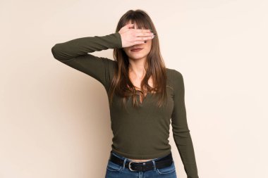 Genç kadın gözleri eller tarafından kapsayan koyu sarı arka plan üzerinde. Bir şey görmek istiyor musunuz