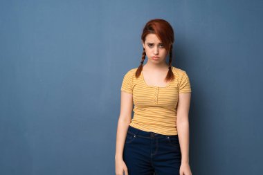 Üzgün ve depresyonda ifade ile mavi arka plan genç Kızıl saçlı kadın