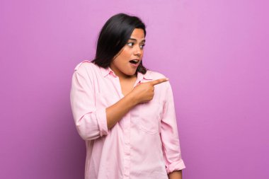 Kolombiyalı genç kız şaşırttı ve yan işaret eden Mor duvarın üzerinden