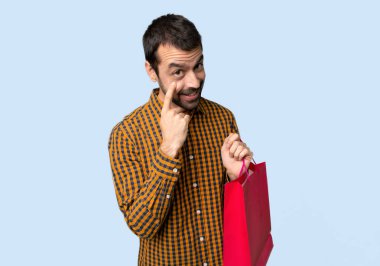 İzole mavi arka planda ön arayan alışveriş çantaları ile adam