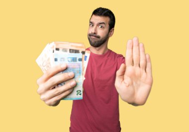 Adam izole sarı arka plan üzerinde bir görüş ile hayal kırıklığına için Stop jest yapma para alarak çok