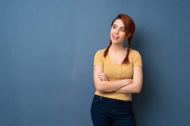 Mavi arka plan gülümseyen süre geçti silah tutan genç Kızıl saçlı kadın