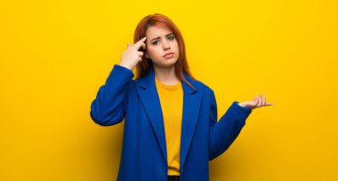 Genç Kızıl saçlı kadın trençkot parmak kafasına koyarak delilik jest yapma ile