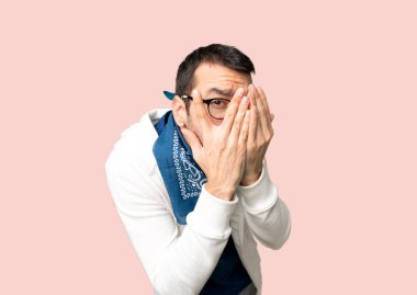 Gözlerle gözleri kaplayan ve izole pembe arka planda parmaklarla görünümlü yakışıklı adam