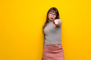 Sarı duvarın üzerinden gözlüklü kadın seni kendinden emin bir ifade ile parmak işaret