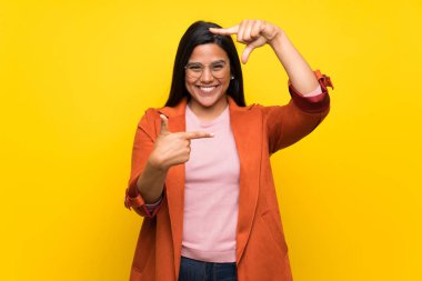 Kolombiya kız yüz odaklanarak sarı duvarın üzerinden. Çerçeve sembolü