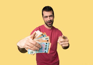 İzole sarı arka planda gülümsüyor iken adam para puan parmak almak