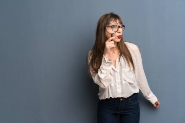 Kadın gözlük Büyüteç alarak ve içinden seyir mavi duvarın üzerinden